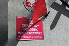 Flaga Polski wisząca obok tablicy z nazwą Ośrodka.
